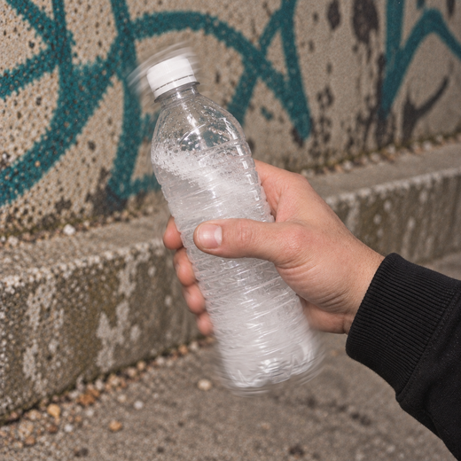 A hand shaking the capped bottle, the water gone clear